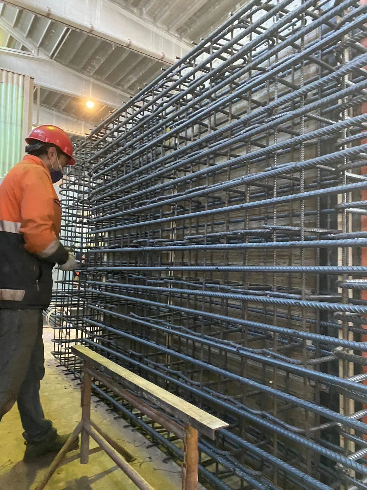 Operaio accanto a una gabbia d'armatura alta diversi metri